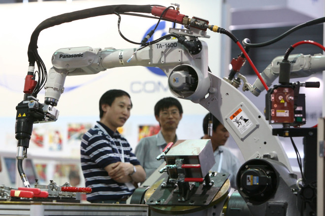 Visitors look at robot arms of Panasonic on display during the China International Robot Show 2013 in Shanghai, China, 2013.