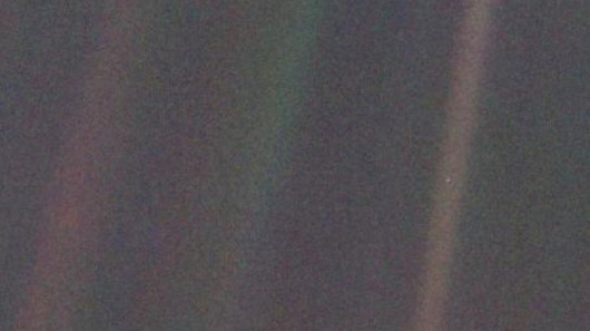 Voyager 1's iconic pale blue dot, with Earth featured as a tiny spec to the right of the i...
